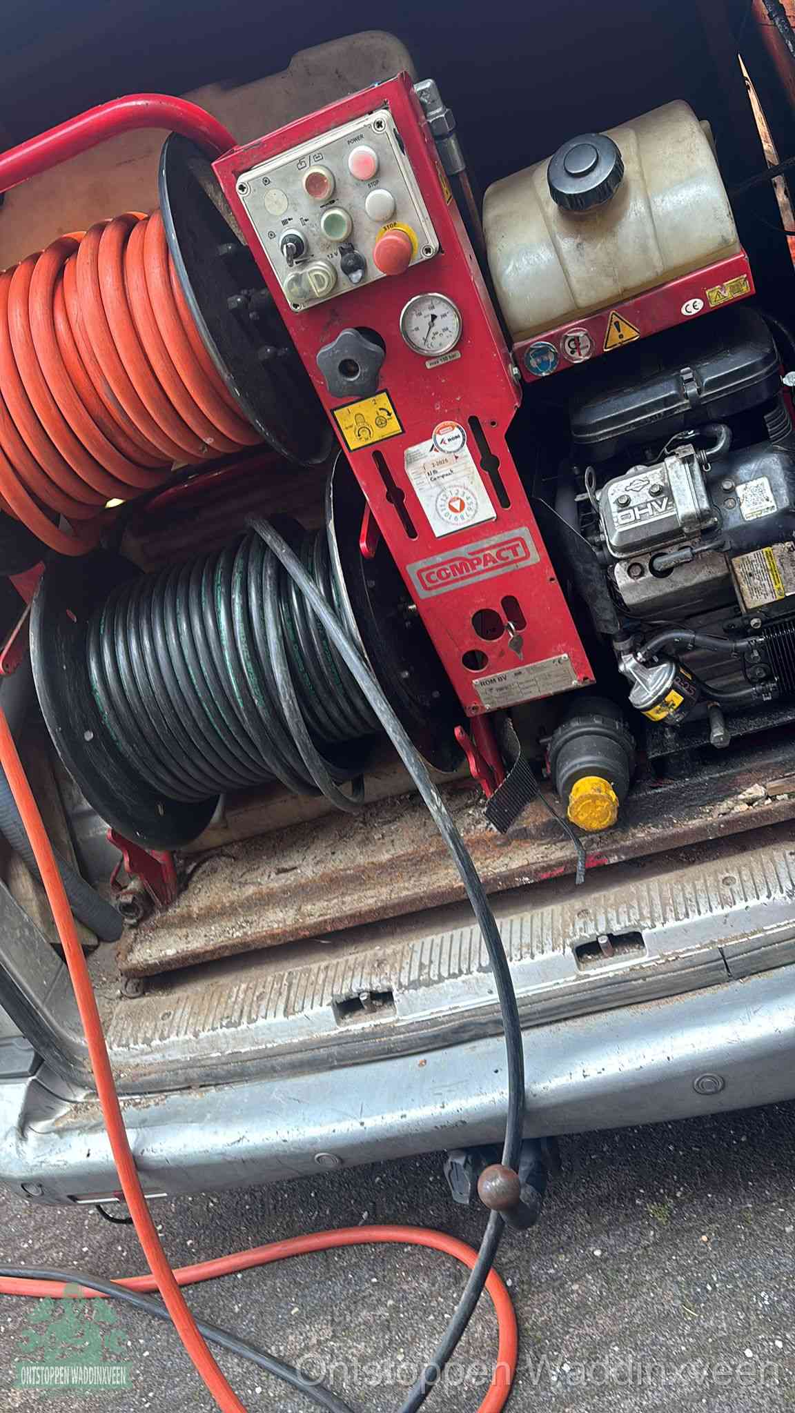 Een rood hogedruk-rioolreinigingstoestel in de laadbak van de bedrijfsbus, apparatuur voor een hardnekkige afvoerverstopping in Waddinxveen