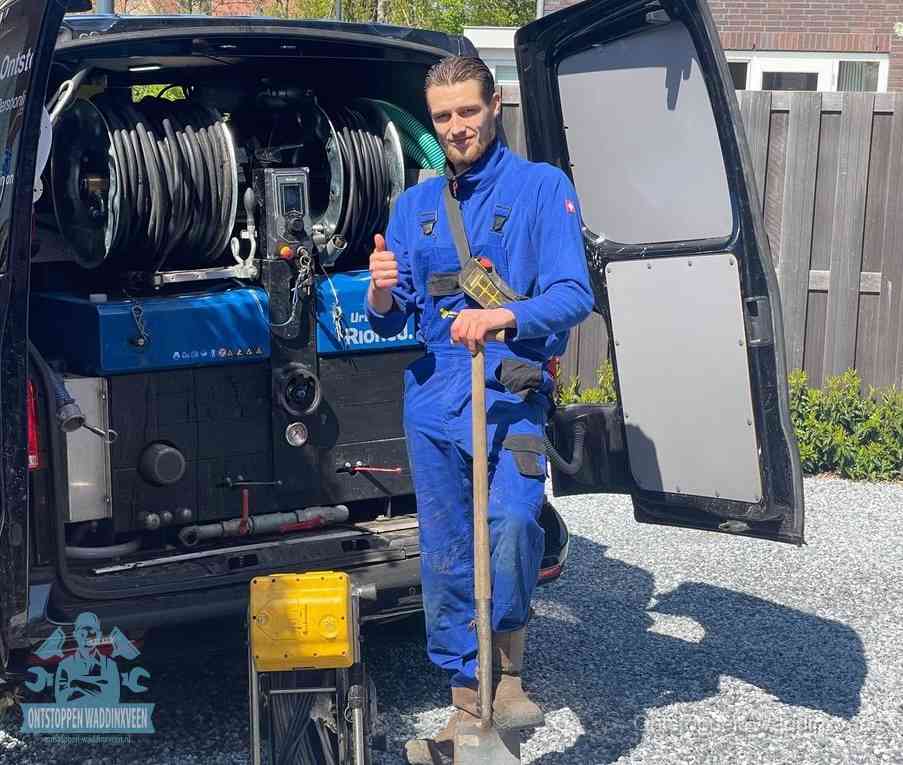 Een monteur bij de werkbus met grote hogedruk-slanghaspels, apparatuur voor hardnekkige afvoerverstoppingen in Waddinxveen