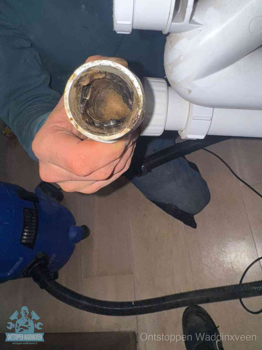Een losgekoppelde afvoerbuis die van binnen volledig is dichtgeslibd met vet en aanslag, de meest voorkomende oorzaak van een verstopte gootsteen in Waddinxveen