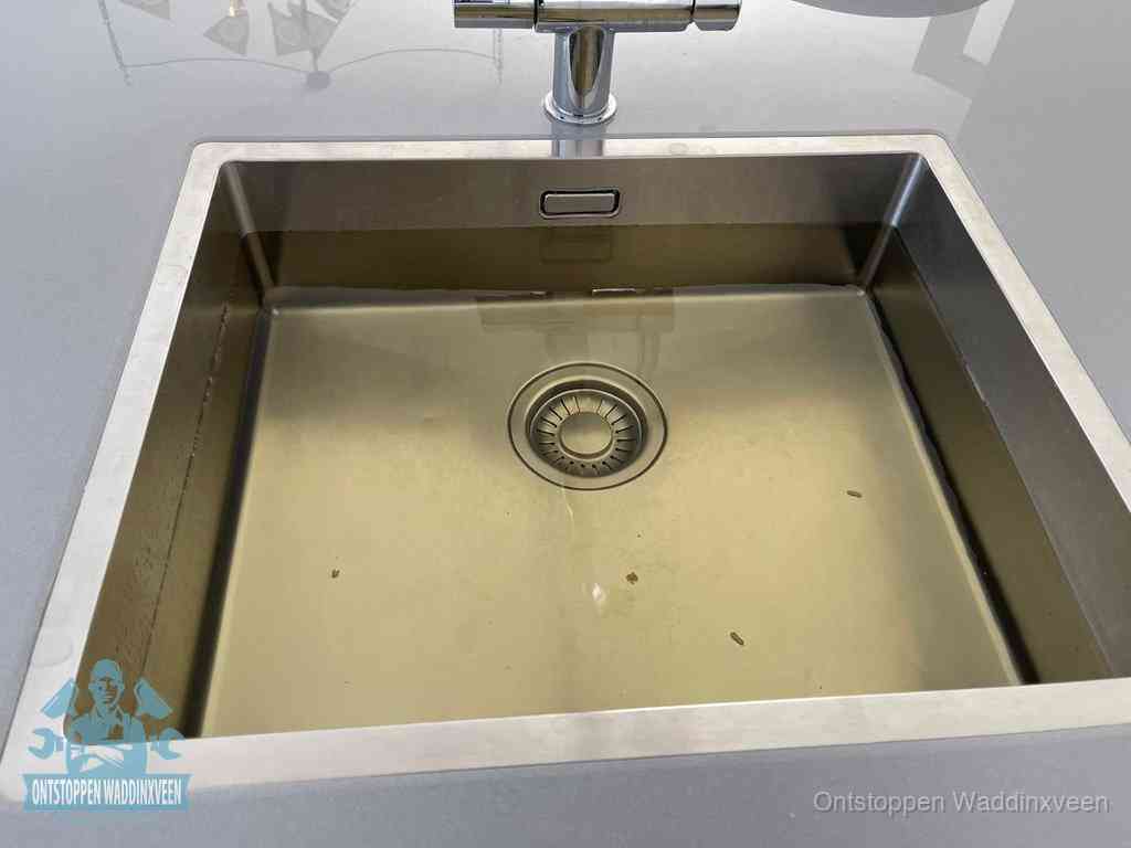 Stilstaand water in een rvs spoelbak dat niet wegloopt, een duidelijk signaal van een gootsteenverstopping in Waddinxveen