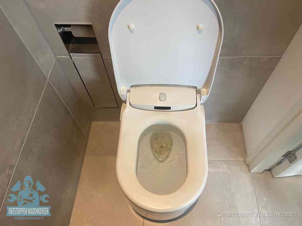Een wit hangtoilet waarin een prop wc-papier op het water blijft drijven, een duidelijk signaal van een verstopte wc in Waddinxveen