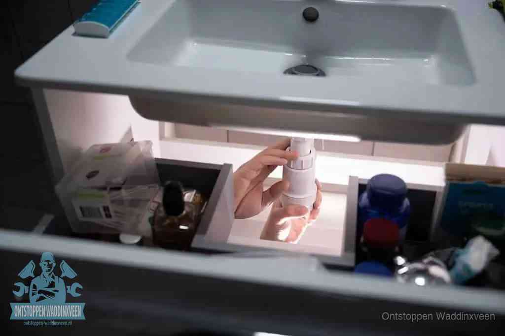 Een pompfles met zeep boven een wastafel in de toiletruimte, de warm water en afwasmiddel-methode om de wc te ontstoppen in Waddinxveen