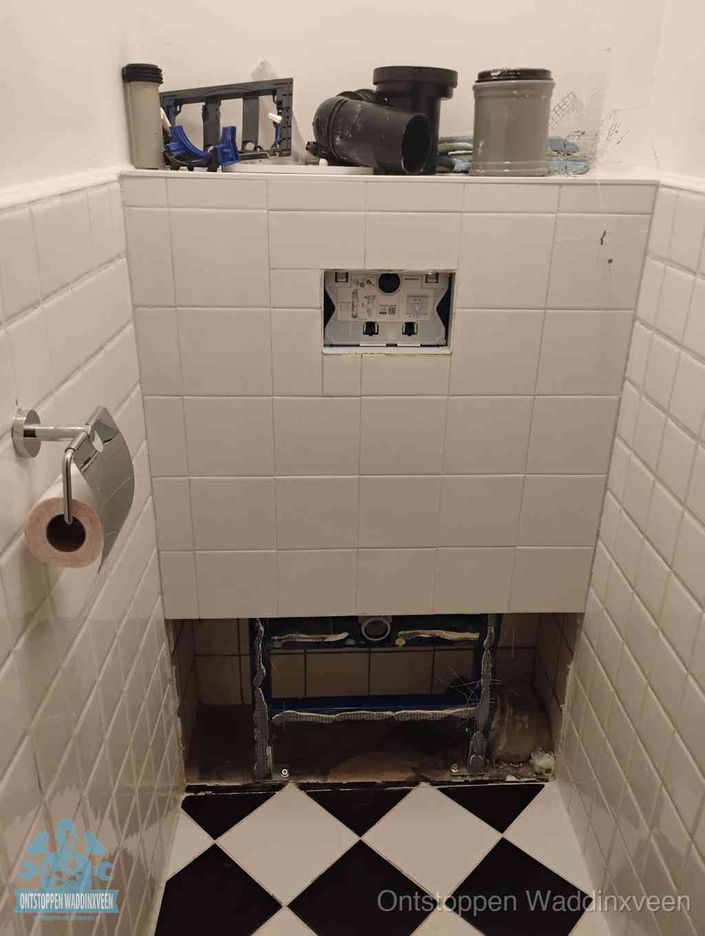 Een toiletruimte waar het hangtoilet en de inbouwreservoir-onderdelen zijn vrijgelegd voor onderhoud, periodiek nazicht voorkomt een wc-verstopping in Waddinxveen