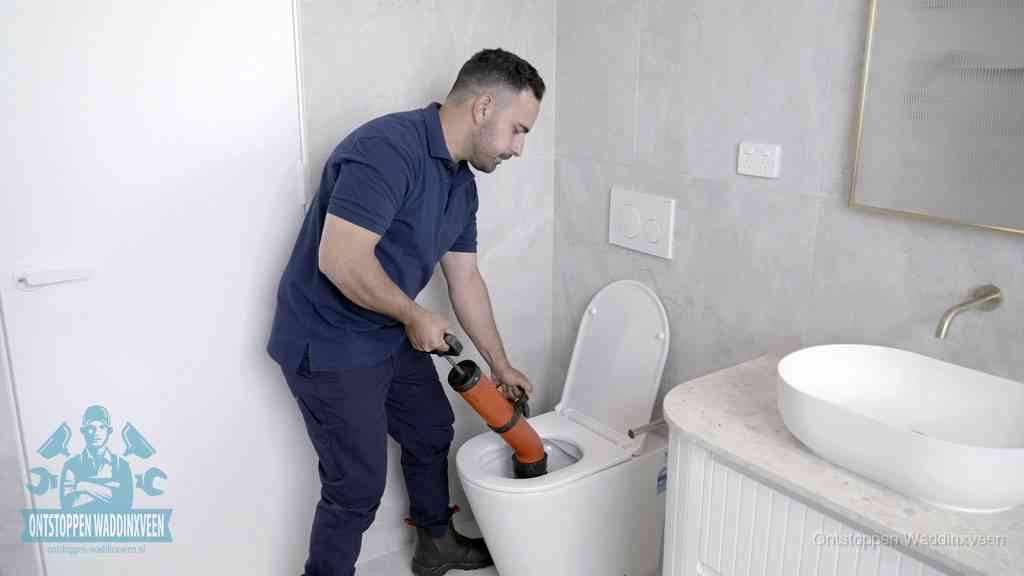 Een monteur gebruikt een handmatige perspomp (toiletontstopper) op een wandcloset tijdens het professioneel wc ontstoppen in Waddinxveen